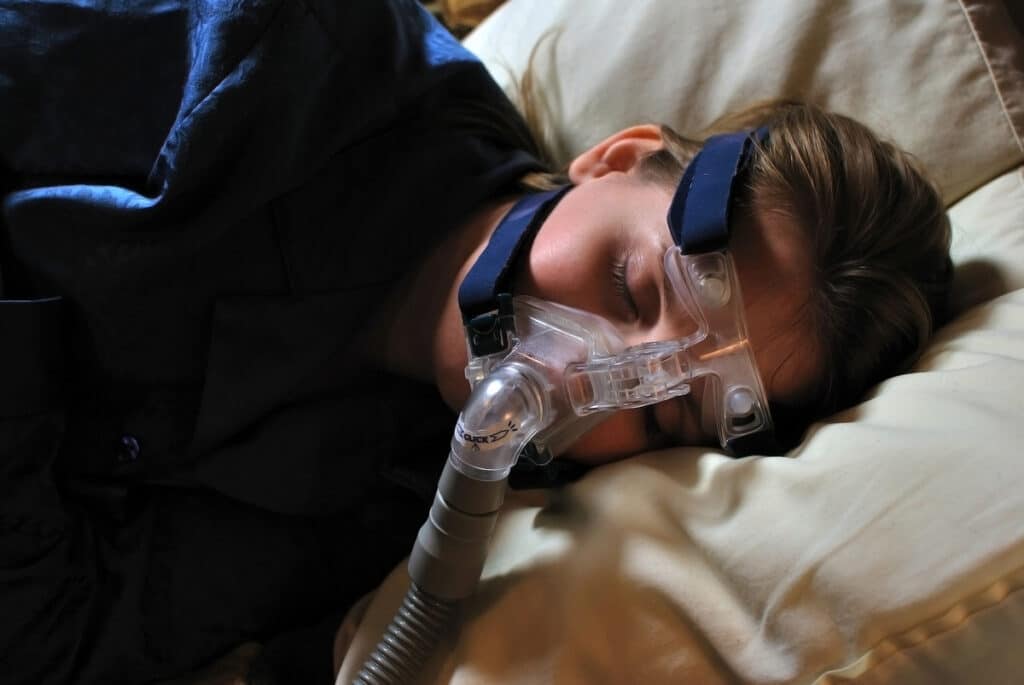 A Woman Sleeping With A Cpap Mask As Part Of An Effective Treatment For Sleep Apnea, Ensuring Proper Airflow And Improved Sleep Quality.