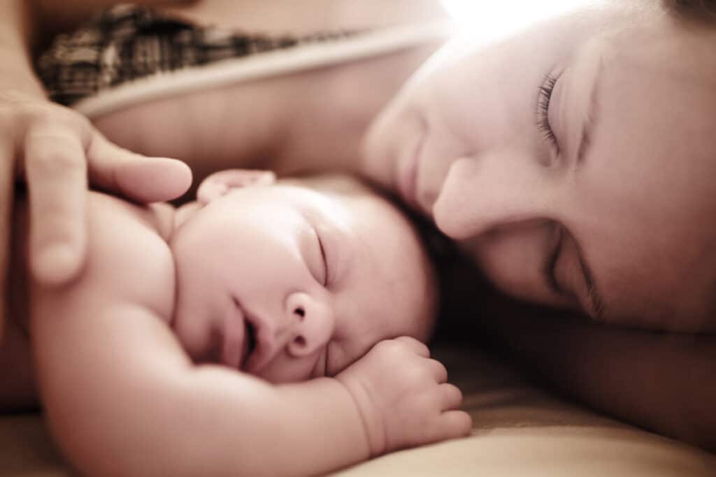 A peaceful moment between a mother and her sleeping baby, representing the success of baby sleep training for better rest and healthy sleep habits.