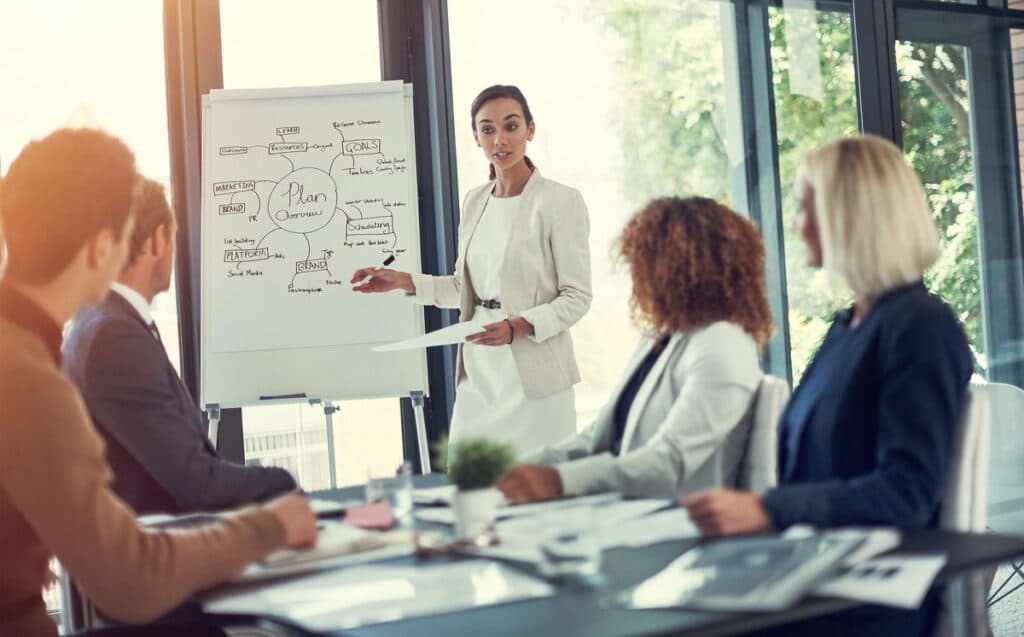 A professional presenting a detailed plan during a meeting, symbolizing the essential sleep coach skills and qualities needed for building a successful career.